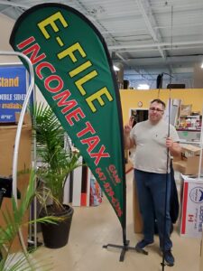 Green custom printed teardrop flag with yellow and red lettering in a showroom