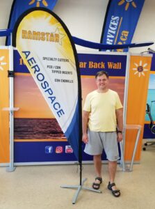 Yellow and white custom printed teardrop flag on a cross base in a showroom