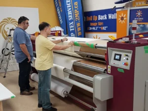Two men at a large-format printer printing a fabric graphic