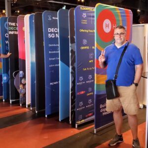 Man in front of a row of colourful tube displays at an expo