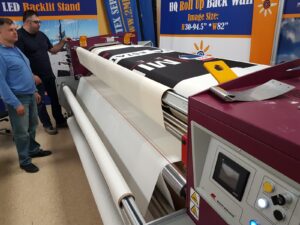 Two men at a large-format printer printing a fabric graphic