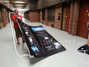 Man unrolling a curved fabric graphic in a hallway