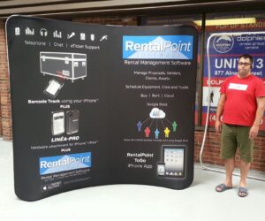 Man beside a black an 8 ft curved tube fabric display with white product text
