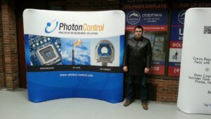 Man beside an 8 ft curved tube fabric display with a blue and white graphic in the showroom