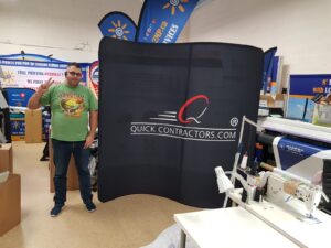Man beside a black an 8 ft curved tube fabric display with a white logo