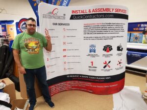 Man beside a white an 8 ft curved tube fabric display listing services
