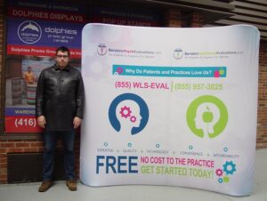Man beside a white an 8 ft curved tube fabric display with colourful round icons