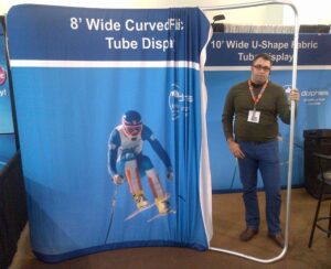 Man beside an 8 ft curved tube fabric display with the frame showing at one side