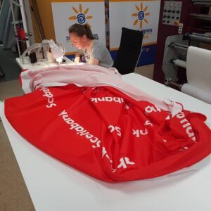 Sewing station finishing a red printed fabric graphic